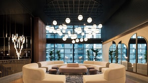 A modern lobby with a circular seating area, large windows, and a unique ceiling light fixture.