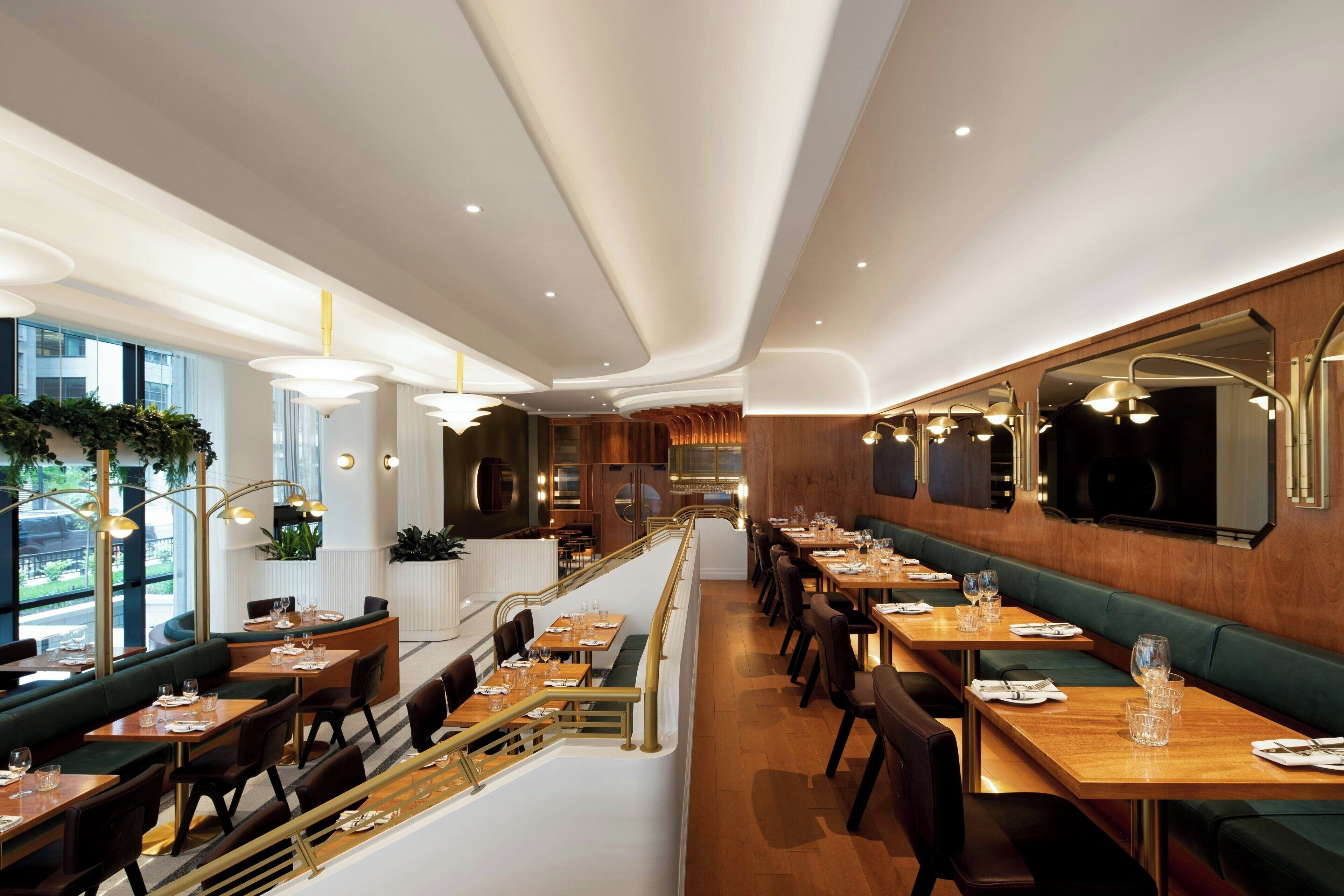 Un restaurante moderno con barra central, techos altos y vistas al exterior.