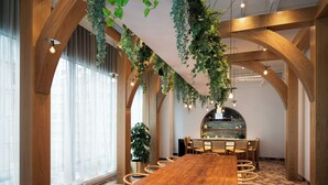 A conference room with a long wooden table, chairs, and hanging plants.