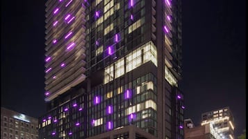 Un edificio moderno de gran altura con fachada de vidrio y detalles de iluminación morada.