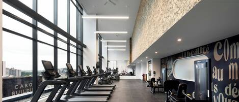 A modern gym with treadmills, stationary bikes, and weight machines.