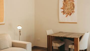Een moderne woonkamer met een houten salontafel, een bank, een eettafel met stoelen en een vloerlamp.