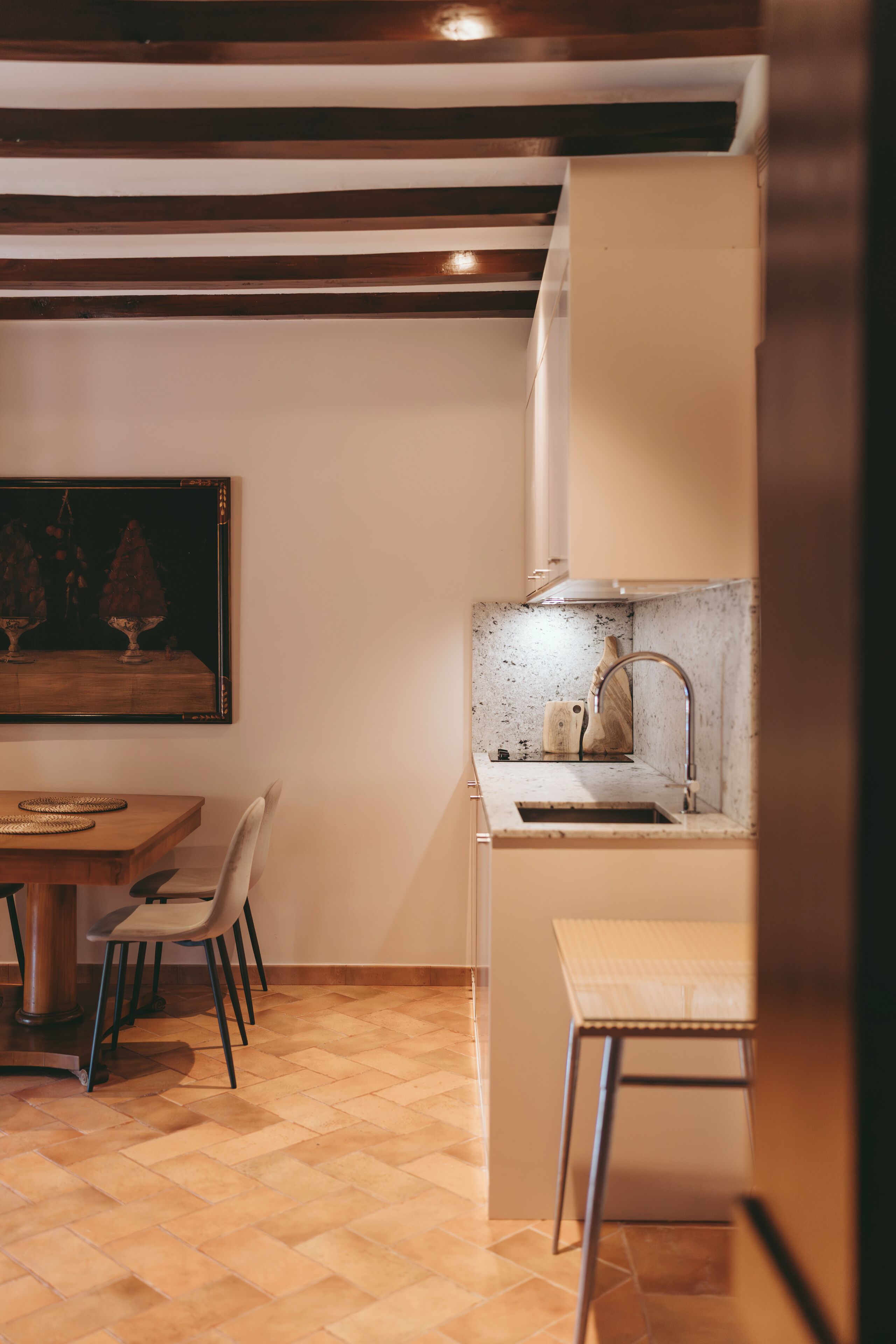 Cocina compacta con una mesa de comedor de madera, sillas y una pequeña isla con pileta.