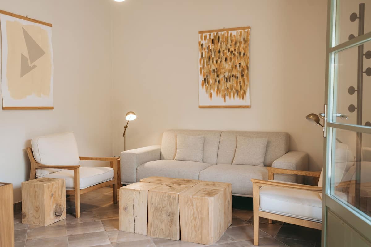 A modern living room with a beige sofa, wooden chairs, a coffee table, and a floor lamp.