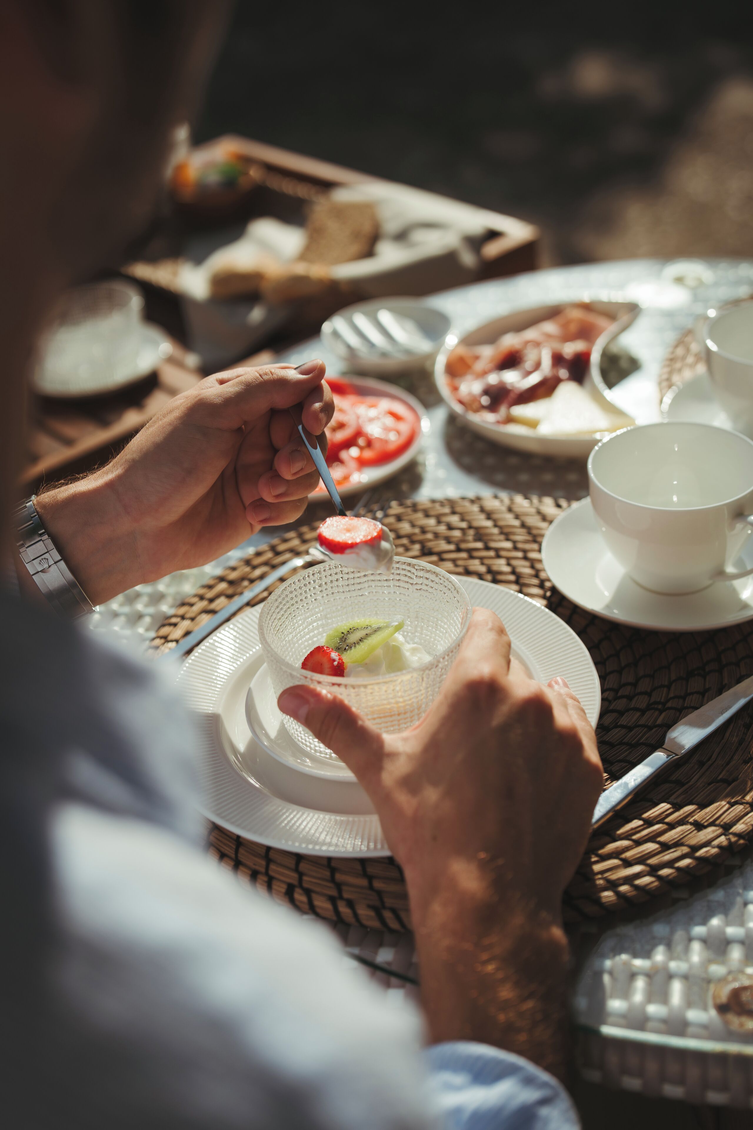 A dining table with various dishes, including a plate with sliced fruit and a cup of tea.