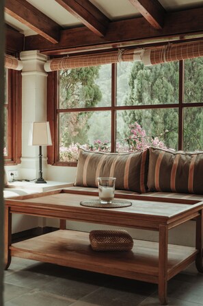 A cozy room with a wooden bench, a table with a glass, and a window with a view of trees and flowers. - Rondaia Boutique Vineyard Stay – Mallorca, Tramuntana (Esporles)