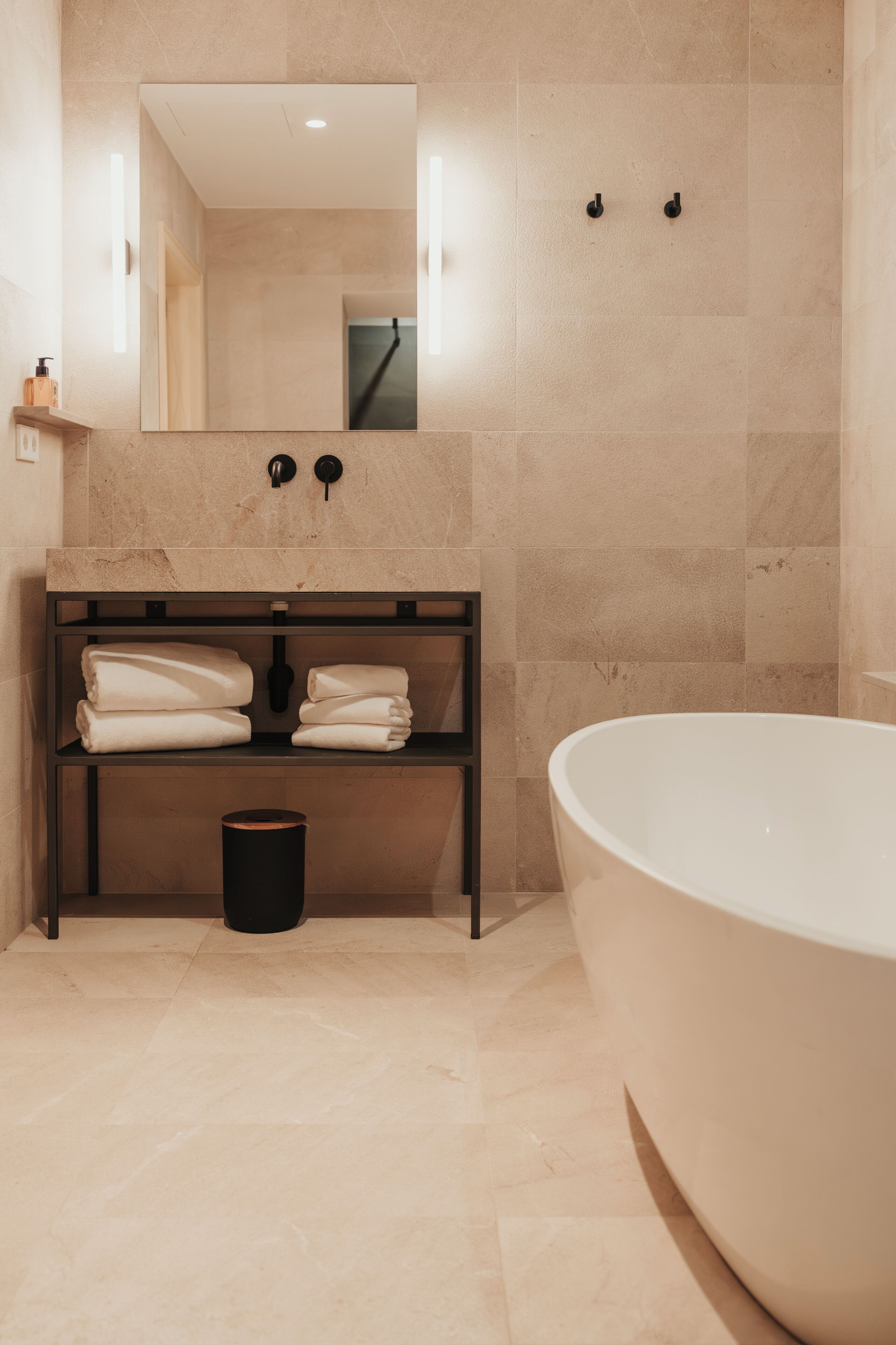 A modern bathroom with a freestanding bathtub, a vanity with towels, and a mirror above the sink.