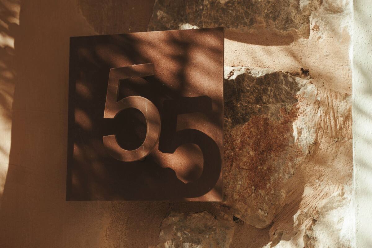 A number '55' on a wall with a rough texture, possibly indicating a room number or location within a building.
