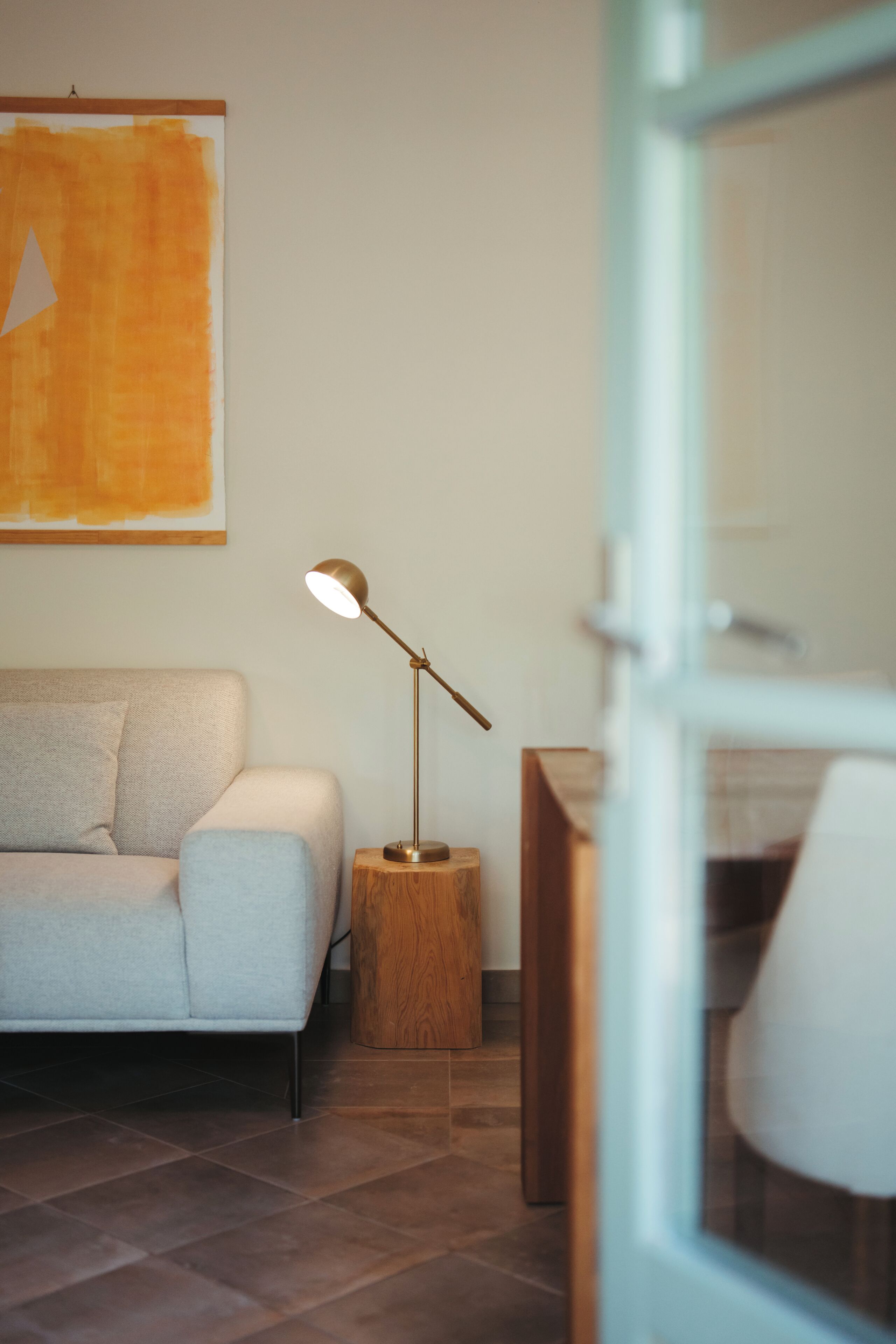 Ett modernt vardagsrum med en soffa, en golvlampa och en tavla på väggen.