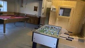 Huoneessa on biljardipöytä, puukaappeja ja pöytäjalkapallopeli.