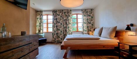 Una camera da letto con un letto, un comodino, una lampada e un televisore montato a parete.