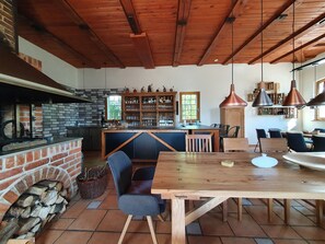 Eine rustikale Küche mit Backsteinwand, Holzbalkendecke und einer Bar mit Regalen voller Flaschen und Gläsern.