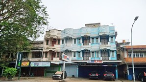 Ein mehrstöckiges Gebäude mit blauer Fassade, einem grünen Schild und einer geschlossenen Garagentür.