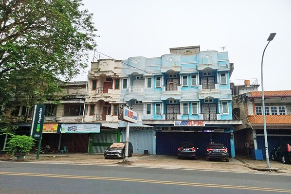 A multi-story building with a blue facade, a green signboard, and a closed garage door.