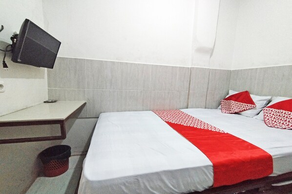 A hotel room with a bed, a desk, and a television mounted on the wall. - Hotel O Benteng Kost (Jambi)