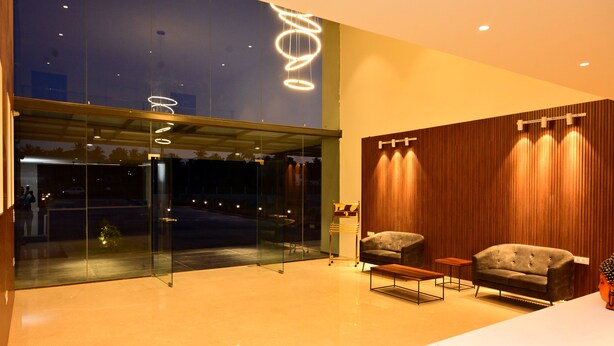 A modern lobby with a glass entrance, two sofas, a coffee table, and a wooden accent wall. - Clarks Inn Express, KRS Road, Mysore (Mysore)