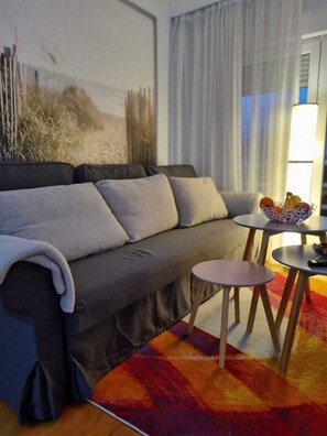 Relax in this inviting living room with a sofa, rug, and single chair, perfect for unwinding with a good book or a bowl of fresh fruit.