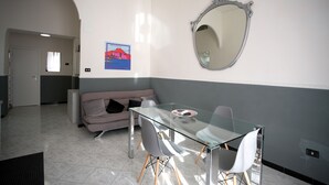 Un salon moderne avec une table à manger en verre, un canapé et un grand miroir au mur.