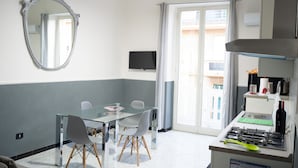Une cuisine moderne équipée d’une cuisinière à gaz, d’un téléviseur à écran plat et d’un coin repas avec une table et des chaises en verre.