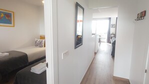 A hotel room with a bed, a bedside table, a mirror, and a window. - Family apartment with pool, gardens and parking in Malaga (Málaga)