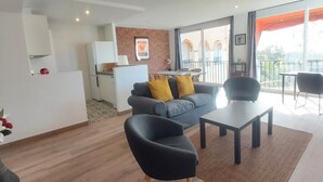 A modern living room with a grey sofa, two black chairs, a small table, and a balcony with a view. - Family apartment with pool, gardens and parking in Malaga (Málaga)