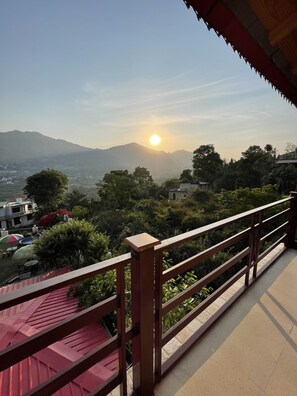 A balcony with a wooden railing overlooking a scenic view of a mountain range and a clear sky. - Sangita Resorts Naukuchiatal (Nainital)