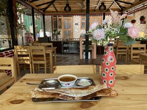 A dining area with wooden tables and chairs, a tray with a dosa, two small bowls of chutney, and a decorative vase with flowers. - Sangita Resorts Naukuchiatal (Nainital)