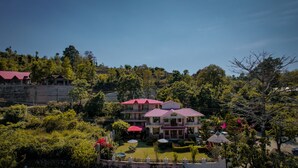 A large, multi-story building with a red roof, surrounded by lush greenery and trees. - Sangita Resorts Naukuchiatal (Nainital)