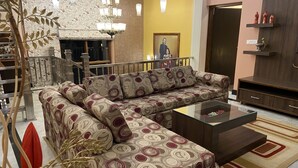 A modern living room with a sectional sofa, a glass coffee table, and a decorative plant. - Sangita Resorts Naukuchiatal (Nainital)