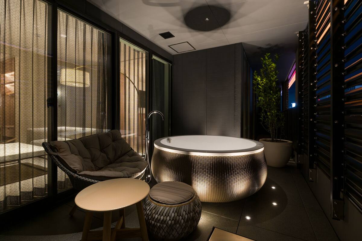 A modern interior with a round seating area, a cushioned chair, a small table, and a large potted plant.