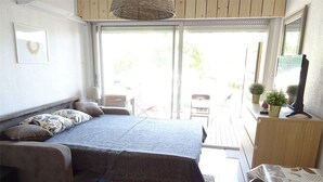 A bedroom with a large bed, a desk, and a chair. There is a window with a view of the outdoors. - Bright Studio with Terrace, Near Shops and Thermal Baths (Balaruc-les-Bains)