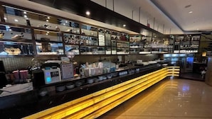 A modern kitchen with a long counter, glass display cases, and a variety of kitchenware. - Youfeel Hotel (Shanghai)