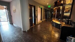 A hotel corridor with a modern design, featuring a curved reception desk with a display case, a series of doors leading to rooms, and a large pillar on the left. - Youfeel Hotel (Shanghai)