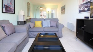 Una sala de estar con un sofá gris, una mesa de centro y un televisor sobre un mueble.