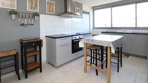 Una cocina moderna con armarios grises, encimera negra y ventana que deja entrar luz natural.