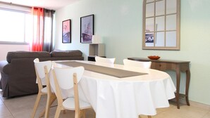 Comedor con una mesa redonda, sillas blancas y una lámpara colgante.