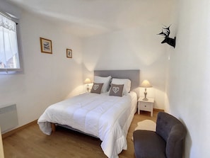 A bedroom with a bed, two bedside tables with lamps, a chair, and a wall-mounted deer head decoration.