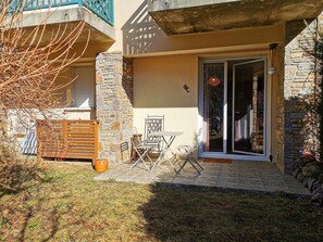 A patio with a table and chairs, a wooden bench, and a stone wall.