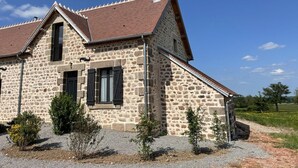 Ein Haus aus Stein mit einem geneigten Dach und einem Schornstein.