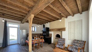 Ein großzügiger Wohnbereich mit Holzboden, Kamin, Esstisch mit Stühlen und einer Couch.