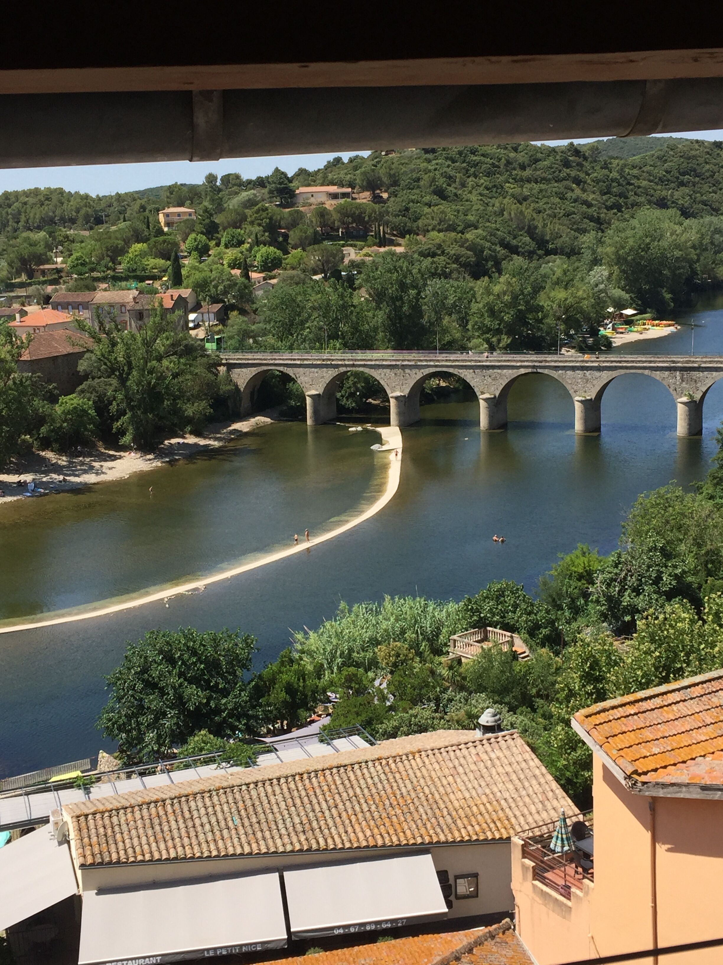 A stone bridge over a river with a town in the background.