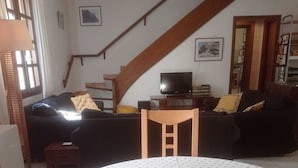 Una sala de estar acogedora con un sofá, una televisión y una mesa con pan y manzanas.