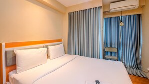 A hotel room with a bed, a chair, an air conditioning unit, and a window with curtains. - Comfort And Cozy Living Studio Room At Tifolia Apartment (Jakarta)