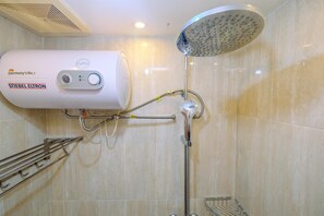 A modern bathroom with a wall-mounted water heater, a handheld showerhead, and a towel rack. - Comfort And Cozy Living Studio Room At Tifolia Apartment (Jakarta)