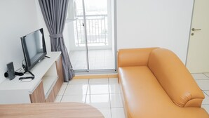 Ein modernes Zimmer mit einer Couch, einem Fernseher auf einem Schrank und einer Glastür, die auf einen Balkon führt.