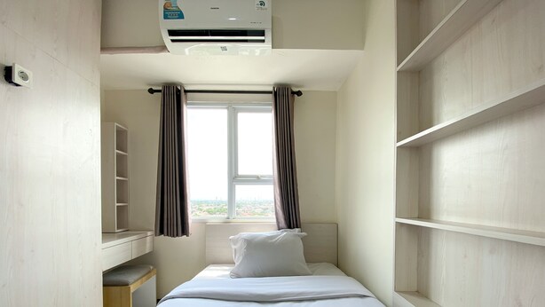 A hotel room with a bed, a window with curtains, a wardrobe, and an air conditioning unit. - Spacious 2Br At 7Th Floor Cinere Resort Apartment (Depok)