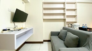 A modern living room with a grey sofa, a mounted TV, and built-in shelves. - Spacious 2Br At 7Th Floor Cinere Resort Apartment (Depok)