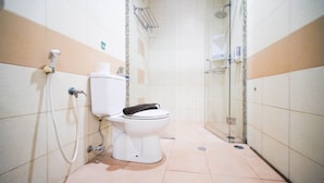 Un baño con inodoro, ducha y zona de ducha con mampara de vidrio.