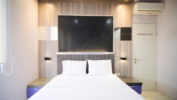 Una habitación de hotel moderna con una cama grande, dos mesitas de noche, un aire acondicionado instalado en la pared y una puerta.
