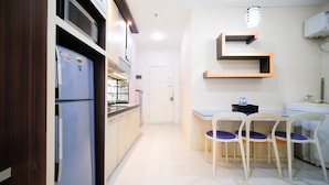 Una cocina compacta con refrigerador, microondas y un pequeño comedor con sillas y una mesa.